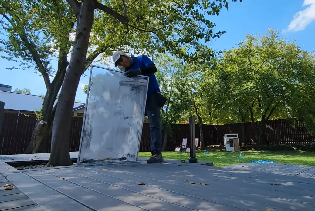 Window cleaner holding a soapy removable window pane upright on a backyard deck