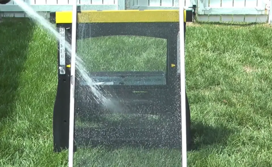 Rinsing a window screen Hose spraying water on a window screen propped up on the grass