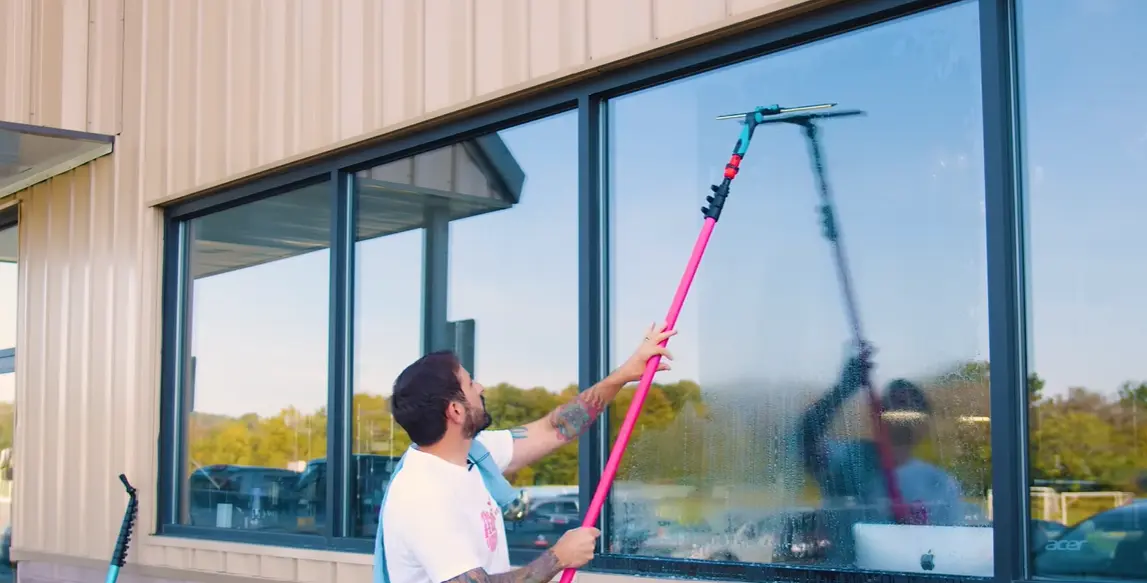 Window cleaning Bend: a cleaner using an extension pole and squeegee on large storefront windows