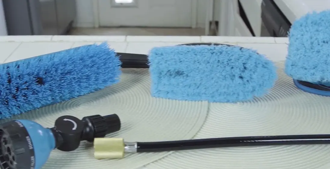 Brush heads and hose nozzle Three blue cleaning brush heads and a hose with a spray nozzle on a table