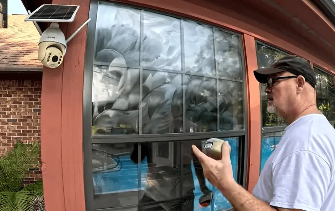 Awbrey Butte window washing Window cleaner holding a scrubber beside soapy panes on a red-trimmed house window